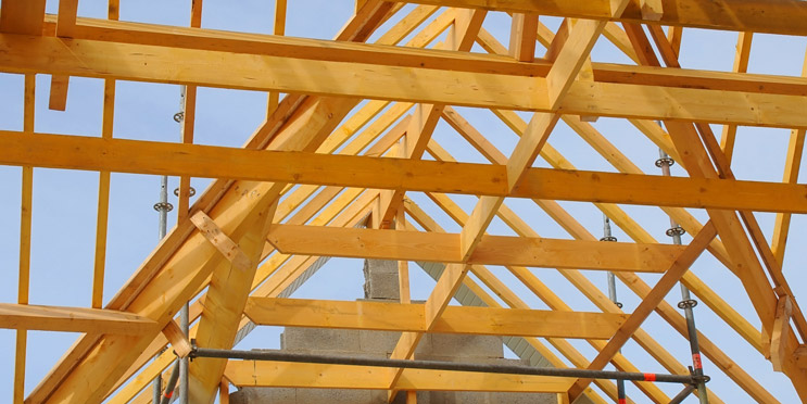 Offene Dachkonstruktion mit sichtbaren Balken aus Massivholz auf Baustelle