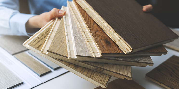 Mehrere Parkett-Muster werden von einer Person in der Hand gehalten, Auswahl unterschiedlicher Holzarten